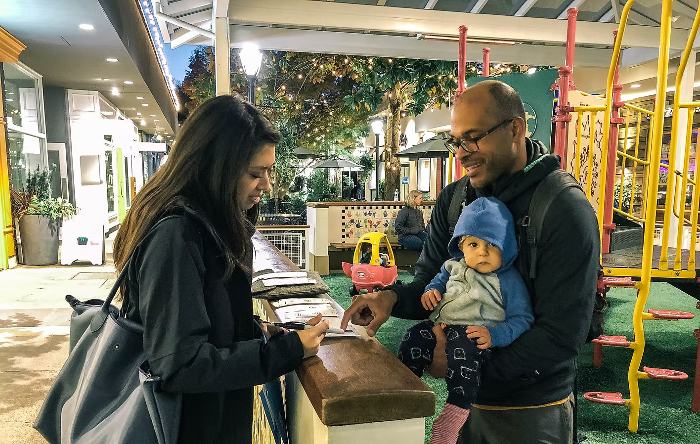 Testing paper prototypes with a dad holding his baby at a playground