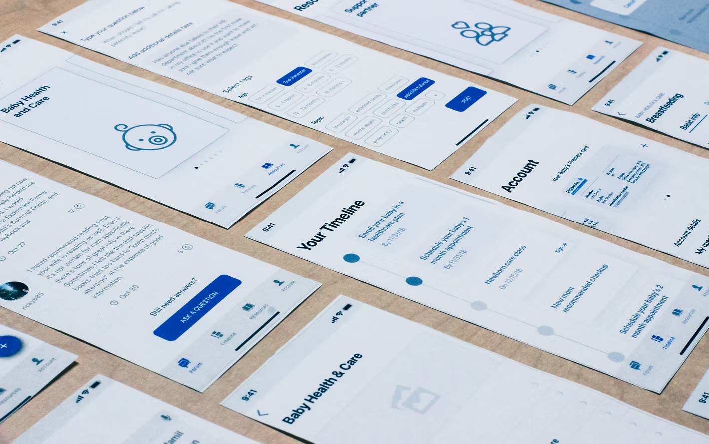 Printed wireframes laid out on a table: timeline, baby health and care, forum and account screens
