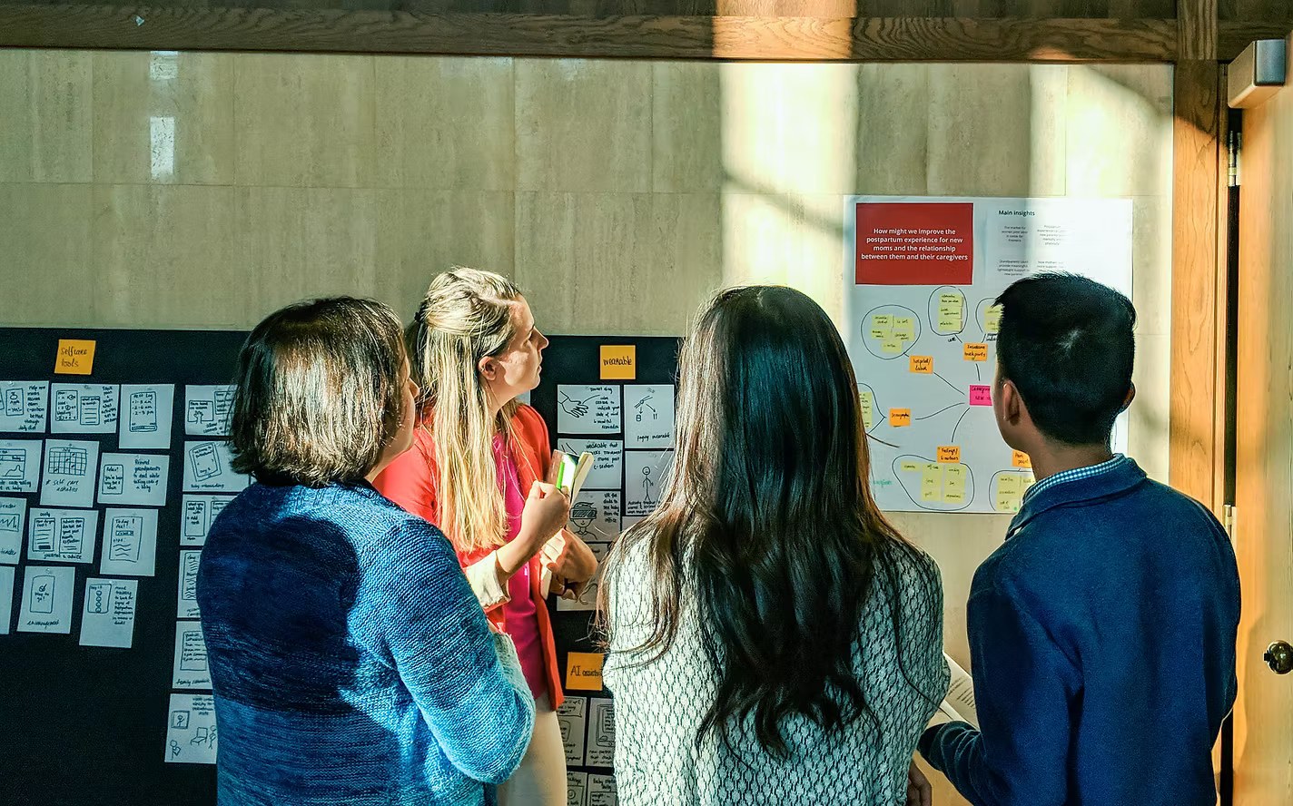 The team reviewing concept sketches and an insights poster on the wall